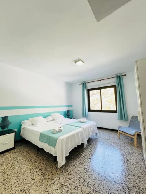 Habitación luminosa en Rocamar con pared turquesa, ropa de cama blanca y equipamientos modernos en Santa Cruz de la Palma