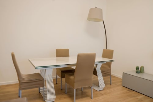 Modern dining area at Treviso Stays with glass table, tan chairs, curved arc lamp, and wooden floor in Ca' Martha apartment.