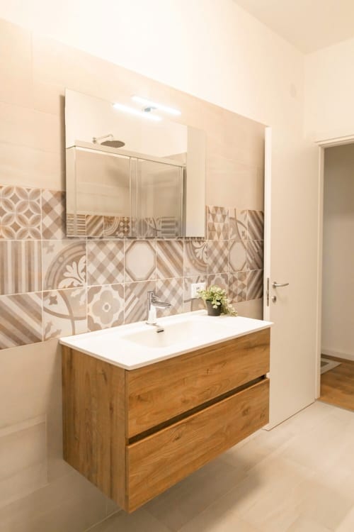 Modern bathroom at Ca' Martha apartment in Treviso with wooden vanity, patterned tile backsplash, and illuminated mirror