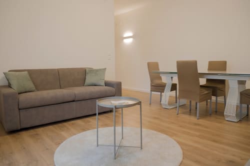 Modern apartment living area with gray sofa, round table, and dining set at Treviso Stays Ca' Martha