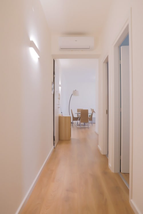 Modern hallway in Ca' Martha apartment in Treviso with wooden flooring, white walls, and doors leading to living spaces