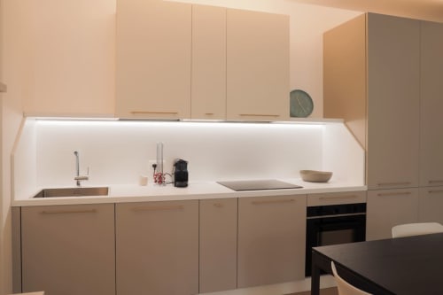 Cucina moderna nell'appartamento Ca' Borsa a Treviso con cabinetry beige, piano cottura bianco, lavello, piano a induzione e forno.