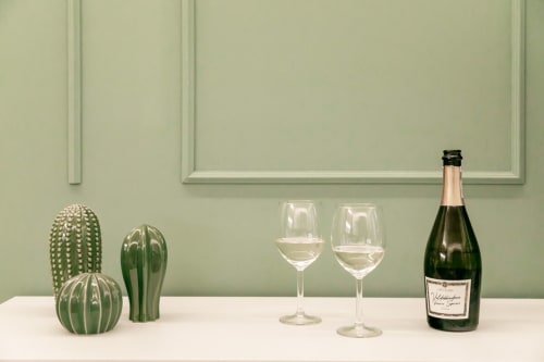 Bottiglia di vino con due bicchieri e cactus su scaffale bianco, arredamento appartamento Treviso