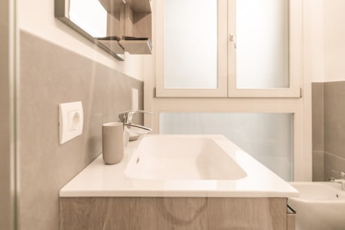 Moderno lavandino da bagno con piano in bianco e rubinetto cromato nell'appartamento Treviso Stays in Italia