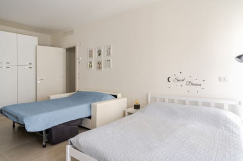 Bright bedroom at Treviso Stays with twin beds, white furniture, and 'Sweet Dreams' wall decal in historic center apartment