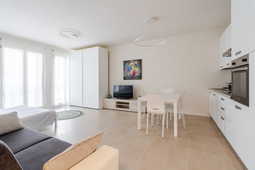 Modern open-plan apartment in Treviso with kitchen, dining area, living space, and balcony access