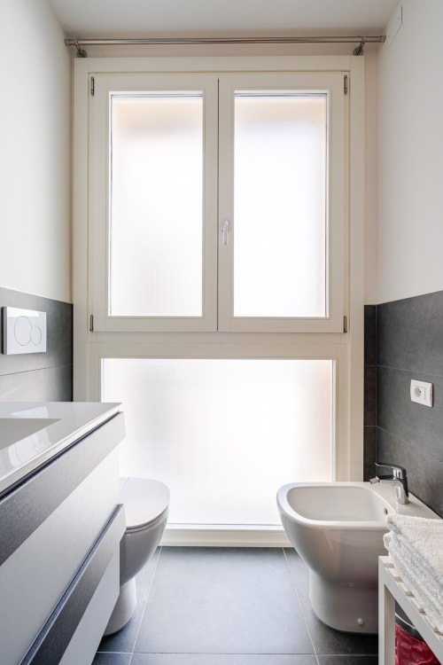 Modern bathroom in Ca' Borsa II apartment, Treviso with bidet, toilet and glass doors leading to patio