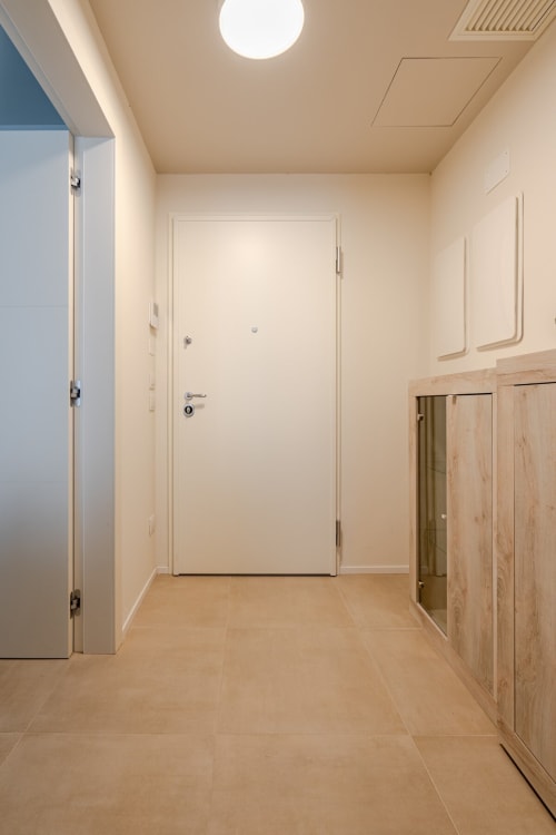 Modern entryway at Ca' Borsa II apartment in Treviso with white doors, light wood cabinets, and neutral tiled flooring