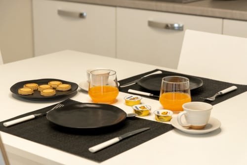 Breakfast spread at Ca' Borsa II apartment in Treviso featuring pastries, orange juice, coffee, and black dinnerware on white