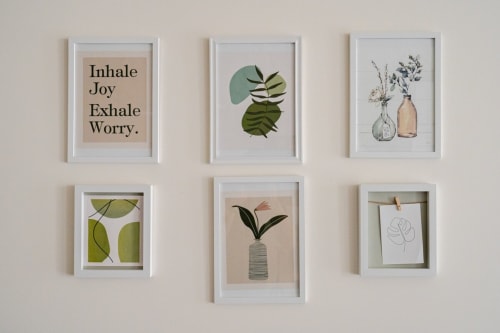 Six framed botanical prints and mindfulness art displayed on beige wall in Treviso apartment.