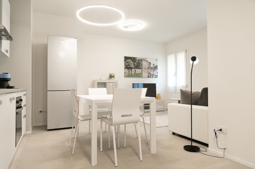 Moderno appartamento open-plan a Treviso con tavolo da pranzo bianco, cucina contemporanea, zona living con divano e elemento circolare