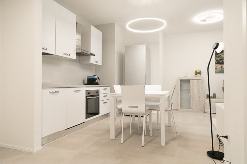 Cucina open-plan moderna e zona pranzo dell'appartamento Ca Borsa III a Treviso con mobili bianchi e tavolo da pranzo
