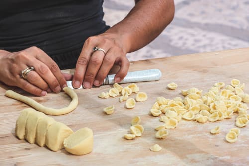 Chef preparing fresh pasta at Al Mirador Resort in Fasano, Italy, cutting dough into shells