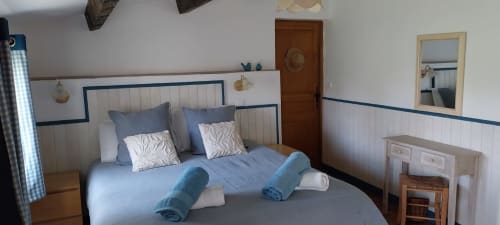 Bright bedroom with blue-striped headboard, rolled towels, and garden view at La Barrat cottage in Monmarvès