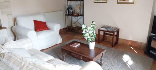Cozy living room in Le Séchoir cottage at La Barrat B&B, Monmarvès, featuring white armchairs, wooden coffee table, and