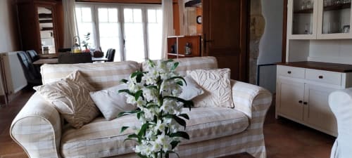 Spacious cottage living room at La Barrat with comfortable sofa, white flowers, and garden views in Monmarvès
