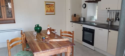 Dining table and kitchen in La Crèche cottage at La Barrat B&B, Monmarvès, France