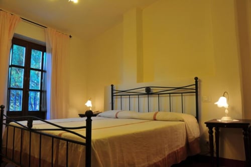 Bright yellow bedroom with metal bed frame and garden view window at Il Casale di Nanni B&B in Lucca