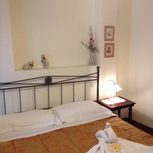 Double bedroom at Il Casale di Nanni B&B in Lucca with iron bed frame, white linens, wooden nightstand, and garden view