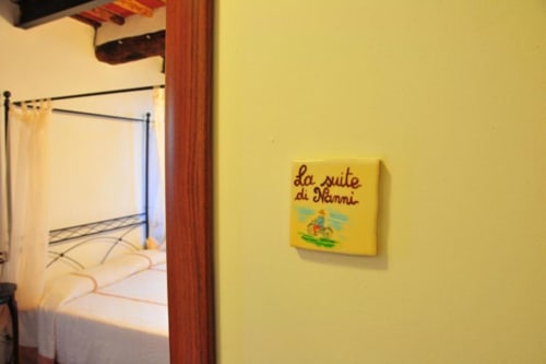 Yellow bedroom hallway at Il Casale di Nanni B&B in Lucca, Italy with canopied bed and Italian signage