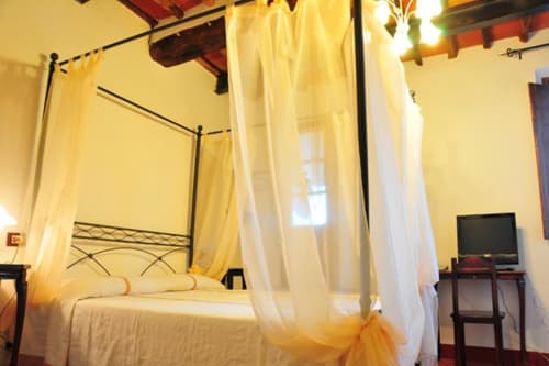 Elegant canopy bed with white sheer drapes in Suite with Balcony at Il Casale di Nanni, Lucca, featuring TV and furnishings