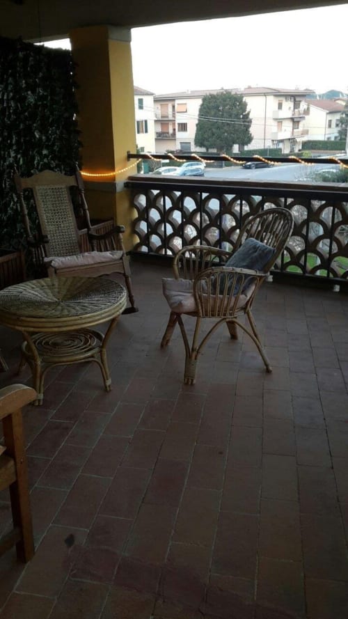 Balcony seating area at Il Casale di Nanni in Lucca with wicker chairs overlooking city buildings and parking area