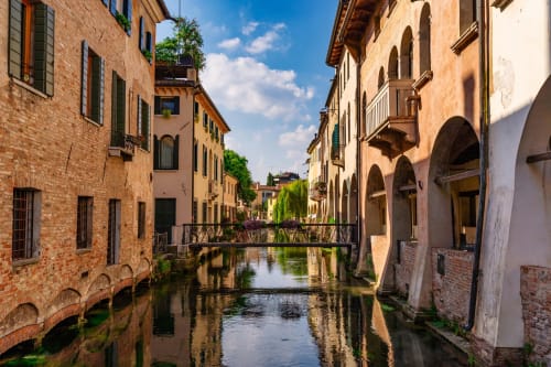 Picturesque canal with medieval brick buildings and wooden bridge in Treviso, Italy. Historic architecture reflecting in