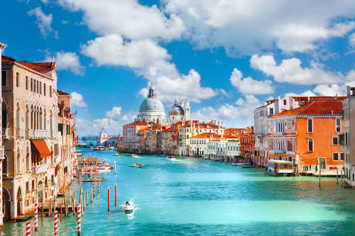 Suggestiva veduta di un canale veneziano con edifici storici colorati, acqua turchese e cupola della basilica vicino a Treviso Stays