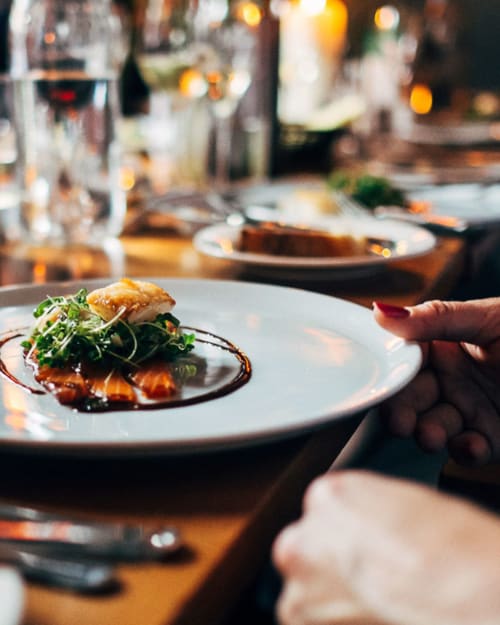 Jantar requintado no Royal Prince Garden Apartments Lisboa: prato de frutos do mar apresentado com microgreens e serviço de vinhos
