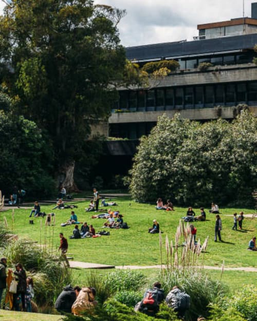 Pátio verde com hóspedes relaxando no Royal Prince Garden Apartments, Lisboa, cercado por arquitetura modernista e vegetação exuberante