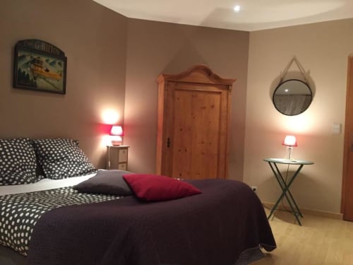 Chambre douillette à La Maison de Marie-Claire avec parure à pois, armoire en bois et éclairage ambiant