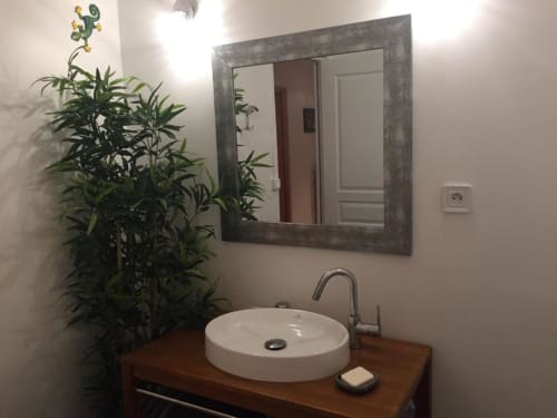 Salle de bain moderne avec vasque ronde blanche, plan de travail en bois, miroir et plante verte à La Maison de Marie-Claire B&B