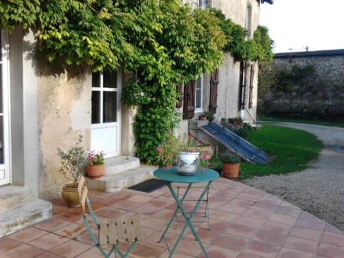 Patio douillet de La Maison de Marie-Claire B&B à Doncourt-sur-Meuse avec table, chaises et murs de pierre couverts de lierre