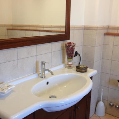 Bathroom in Classic Family Room at Il Casale di Nanni, Lucca with white round sink, mirror, and decorative accessories