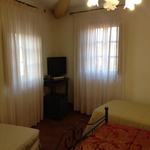 Classic Family Room at Il Casale di Nanni in Lucca with twin beds, TV desk, and garden views through sheer curtains