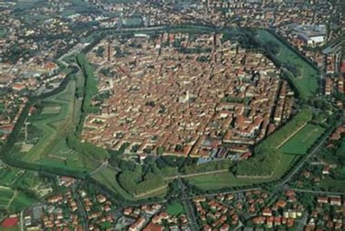 Aerial view of historic walled city of Lucca, Italy with red-roofed buildings and green fortifications surrounding the