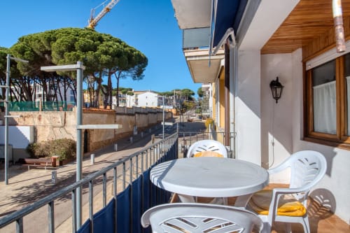 Balcony with white table and chairs overlooking coastal street in Palafrugell, Calella apartment