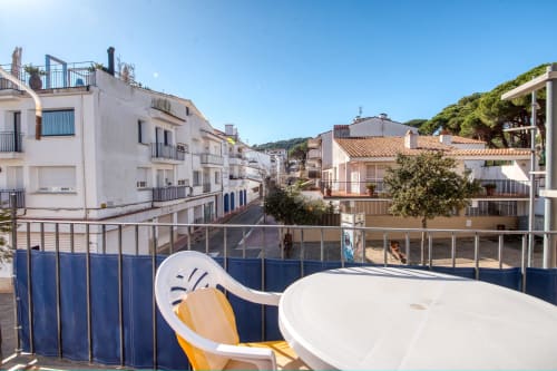 Studio apartment balcony with city view in Palafrugell, featuring white furniture overlooking Mediterranean coastal town
