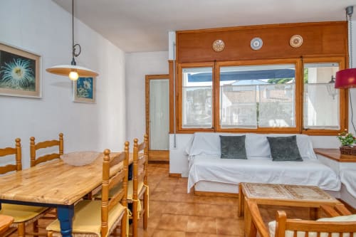 Studio apartment in Calella with wooden furniture, dining table, sofa bed, city views through windows, and modern amenities