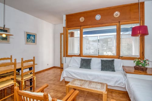 Bright studio apartment in Calella de Palafrugell with wooden furnishings, white bed, city views through large windows, and