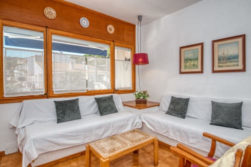 Cozy studio apartment in Palafrugell with two single beds, green pillows, wooden furniture, and city views through large