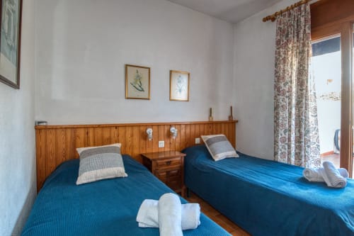 Twin bedroom with blue bedspreads and wooden headboard in Calella de Palafrugell apartment