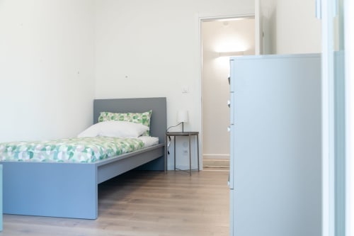 Modern bedroom in Ca' Martha apartment, Treviso with blue bed, green bedding, wooden floor, and wardrobe.