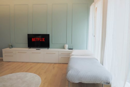 Camera moderna presso Treviso Stays con letto, parquet, TV a parete con Netflix e pareti rivestite in verde chiaro