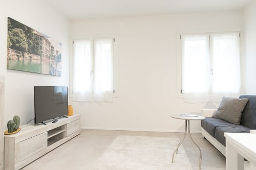 Moderno soggiorno a Treviso con TV, divano grigio, luce naturale dalle finestre e arredi contemporanei