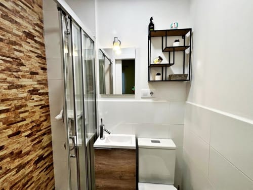 Baño moderno en apartamento Ruliña, Baiona con ducha, lavamanos, inodoro, espejo y estanterías negras