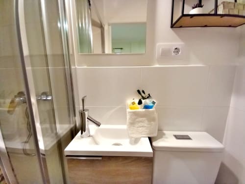 Baño moderno en apartamento Ruliña, Baiona con lavabo blanco, inodoro, ducha y soporte para artículos de higiene