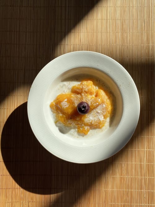 Elegant plated dessert at La Guirtelle B&B Lainsecq, featuring caramelized fruit with cream sauce and dark garnish