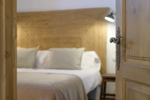 Wooden door opening to bright bedroom with white bedding and headboard at Finca de La Geria cottage