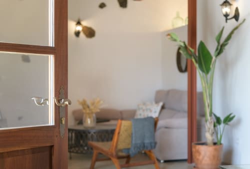 Open wooden door to La Cochera cottage at Finca de La Geria showing garden view with green plants, comfortable seating, and